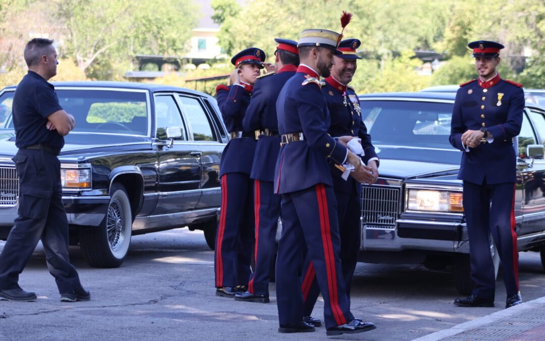 Guardias reales uniformados junto a dos vehículos Cadillac de alta representación.
